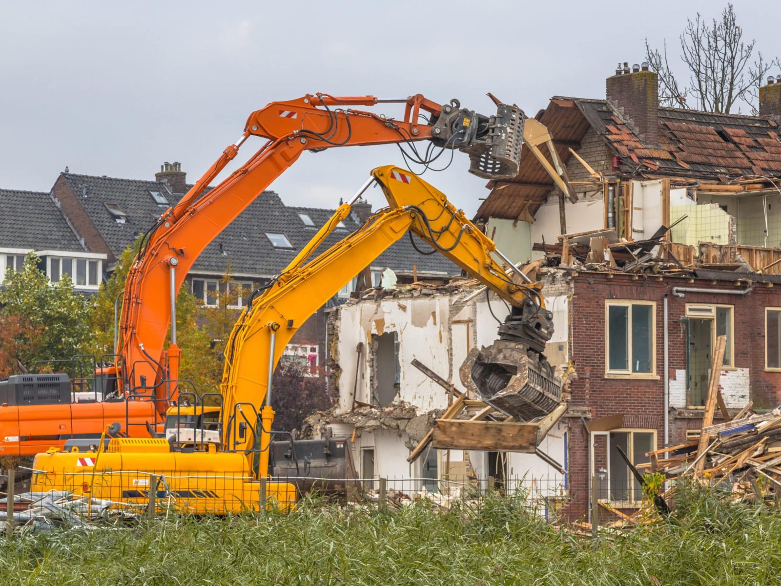 Two Demolition cranes demolishing old row of houses in the Netherlands